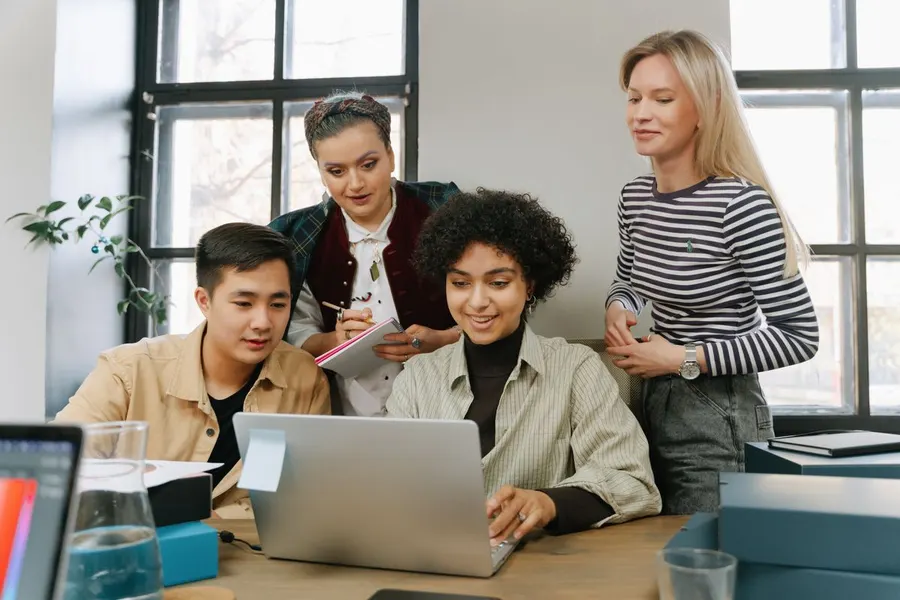 A group of people looking at a laptop, organising their sales pipeline.